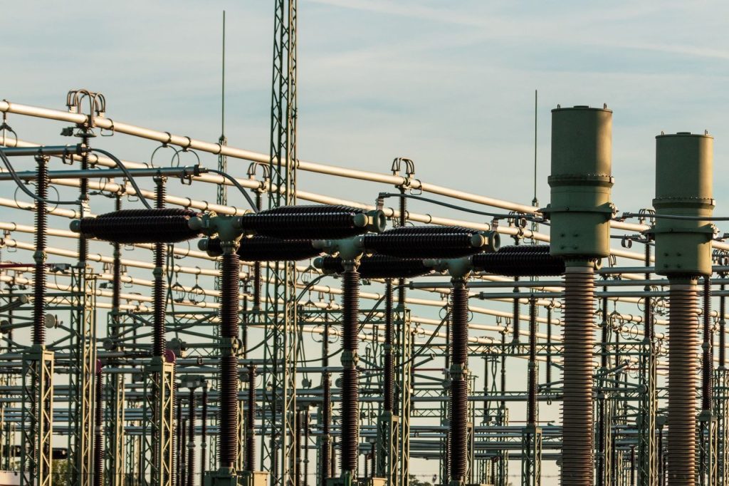 Equipamentos e isoladores de uma subestação elétrica de alta tensão sob céu claro