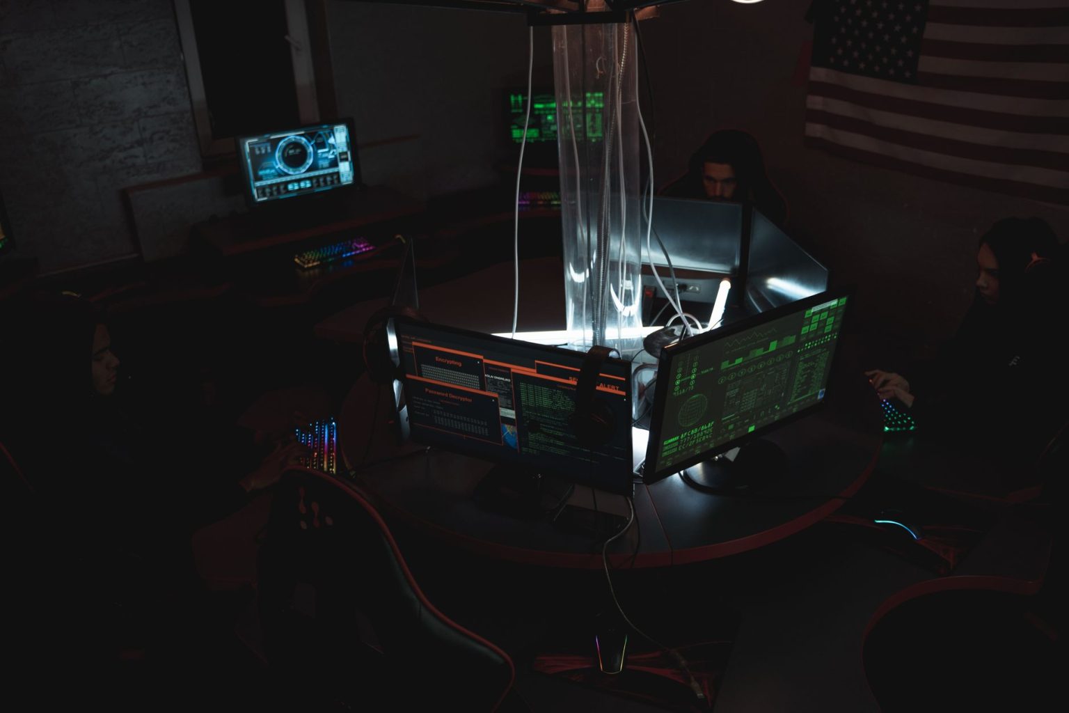 Equipe de profissionais de cibersegurança trabalha em conjunto diante de computadores em uma sala pouco iluminada.